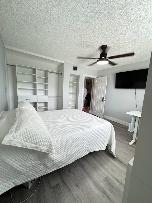 bedroom with wood finished floors, ceiling fan, baseboards, and a textured ceiling