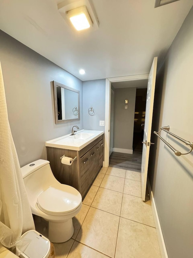 bathroom with toilet, tile patterned floors, vanity, and baseboards