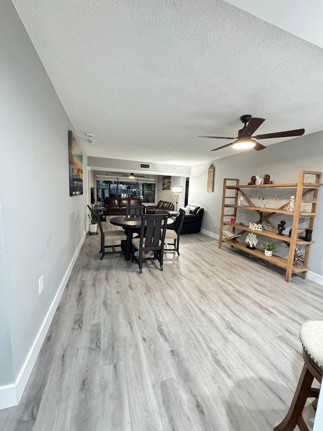 dining space with a textured ceiling, wood finished floors, baseboards, and a ceiling fan