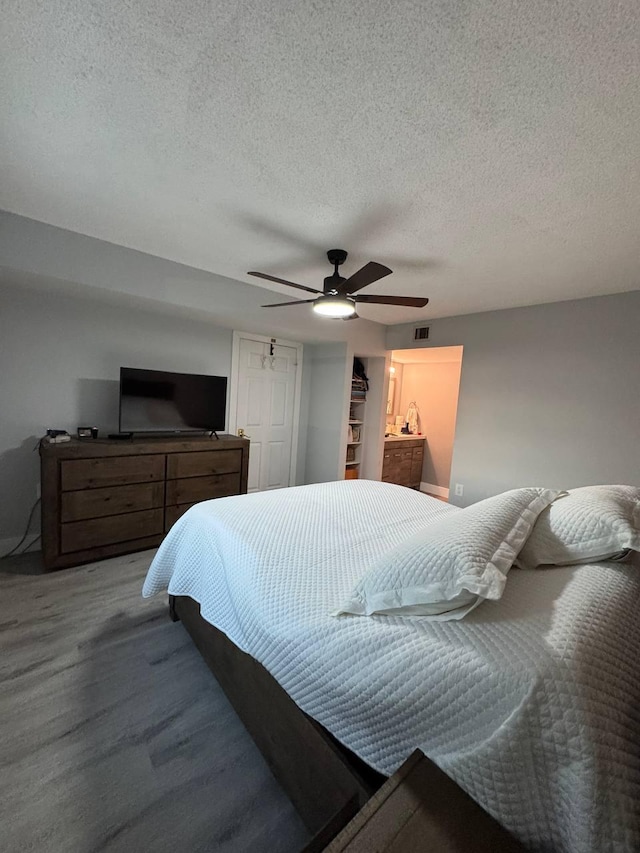 bedroom with wood finished floors, a textured ceiling, ceiling fan, and a closet