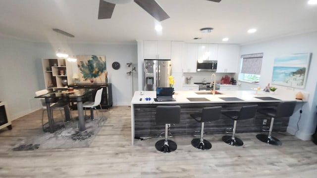 14516 Canalview Dr Unit B, Delray Beach, FL 33484 - kitchen featuring stainless steel appliances, white cabinetry, light wood-type flooring, decorative light fixtures, and light countertops