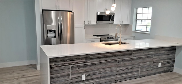 14516 Canalview Dr Unit B, Delray Beach, FL 33484 - kitchen with stainless steel appliances, light countertops, white cabinets, decorative light fixtures, and a peninsula