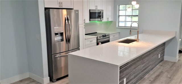 14516 Canalview Dr Unit B, Delray Beach, FL 33484 - kitchen with stainless steel appliances, light wood-style floors, a peninsula, white cabinetry, and light countertops