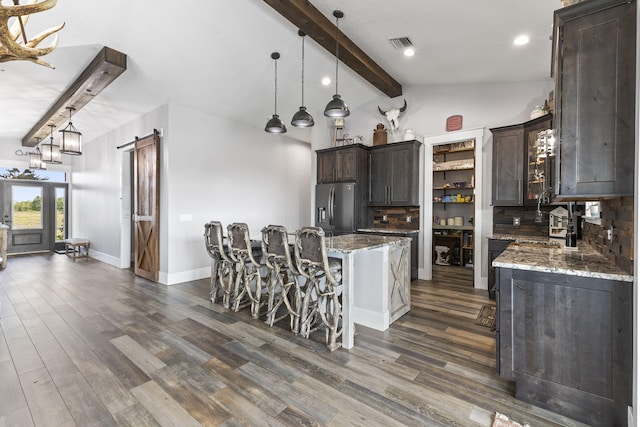 1545 Pulitzer Rd, Fort Pierce, FL 34945 - kitchen featuring stainless steel fridge with ice dispenser, a barn door, dark brown cabinetry, decorative backsplash, and light stone countertops