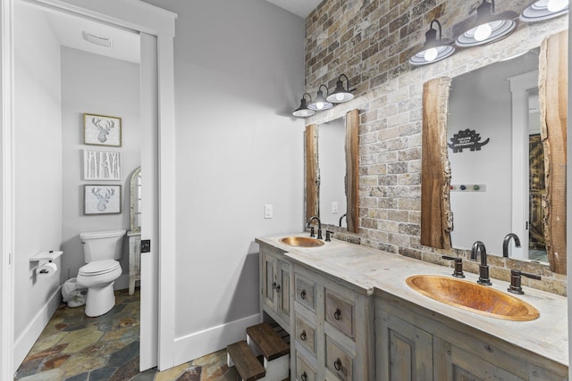 1545 Pulitzer Rd, Fort Pierce, FL 34945 - full bathroom featuring stone tile floors, baseboards, toilet, and double vanity
