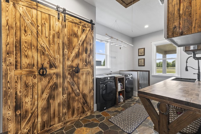 1545 Pulitzer Rd, Fort Pierce, FL 34945 - washroom with washing machine and dryer, dark stone finish flooring, a barn door, and recessed lighting