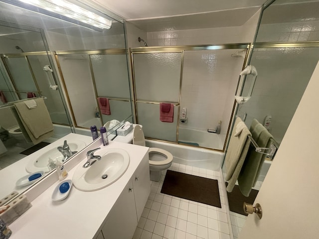 bathroom with toilet, tile patterned floors, vanity, and combined bath / shower with glass door