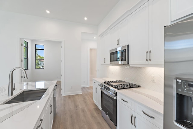 308 SE Via Sangro, Port Saint Lucie, FL 34987 - kitchen featuring stainless steel appliances, a sink, light wood-style floors, decorative backsplash, and light stone countertops
