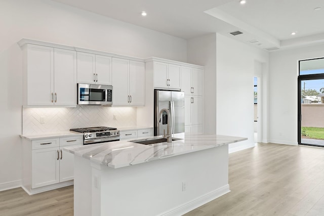 308 SE Via Sangro, Port Saint Lucie, FL 34987 - kitchen featuring appliances with stainless steel finishes, light wood-type flooring, a sink, decorative backsplash, and light stone counters