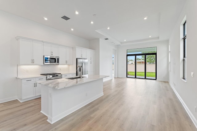 308 SE Via Sangro, Port Saint Lucie, FL 34987 - kitchen featuring appliances with stainless steel finishes, a sink, a center island with sink, decorative backsplash, and light wood finished floors