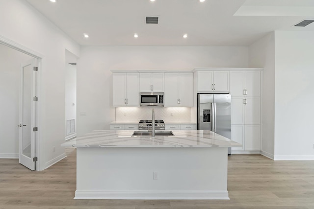 308 SE Via Sangro, Port Saint Lucie, FL 34987 - kitchen featuring appliances with stainless steel finishes, a sink, white cabinets, light wood finished floors, and tasteful backsplash