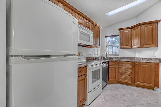 1265 Pine Sage Cir, West Palm Beach, FL 33409 - kitchen featuring white appliances, lofted ceiling, brown cabinetry, light tile patterned floors, and dark stone countertops