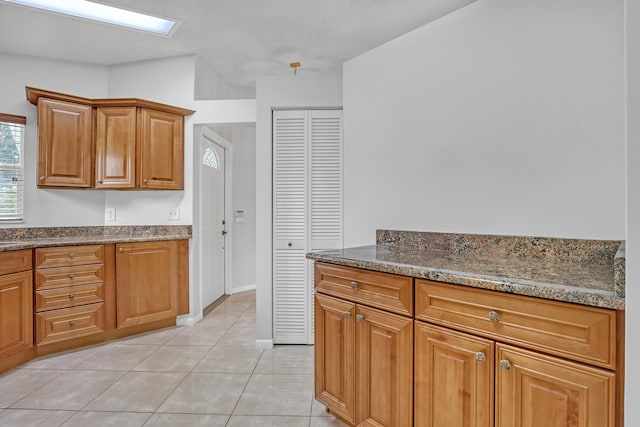 1265 Pine Sage Cir, West Palm Beach, FL 33409 - kitchen featuring light tile patterned floors, dark stone countertops, and brown cabinets