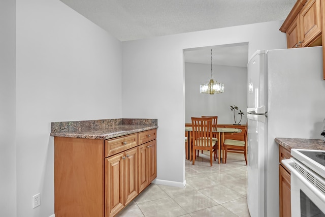 1265 Pine Sage Cir, West Palm Beach, FL 33409 - kitchen featuring a chandelier, light tile patterned floors, dark stone countertops, white appliances, and brown cabinetry