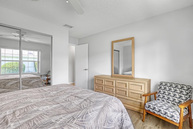 1265 Pine Sage Cir, West Palm Beach, FL 33409 - bedroom with light wood-type flooring, a textured ceiling, a closet, and a ceiling fan
