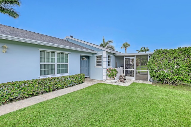 1265 Pine Sage Cir, West Palm Beach, FL 33409 - rear view of house with a sunroom, stucco siding, a yard, and roof with shingles