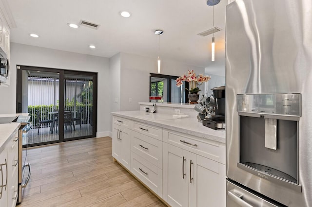 21188 Juego Cir Unit 17-A, Boca Raton, FL 33433 - kitchen with stainless steel appliances, white cabinets, light wood-style floors, light stone counters, and pendant lighting