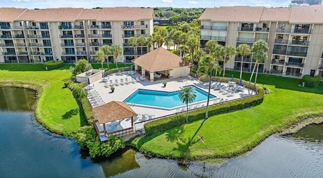 community pool featuring a patio area, a water view, and a yard