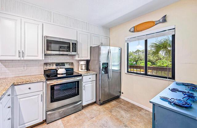 kitchen featuring stainless steel appliances, baseboards, tasteful backsplash, and white cabinets