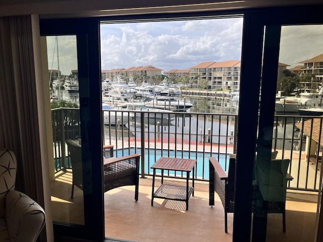 balcony with view of pool area and a water view