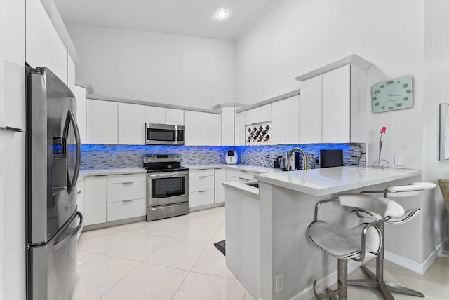 8237 Via Di Veneto, Boca Raton, FL 33496 - kitchen featuring appliances with stainless steel finishes, a peninsula, backsplash, white cabinetry, and recessed lighting