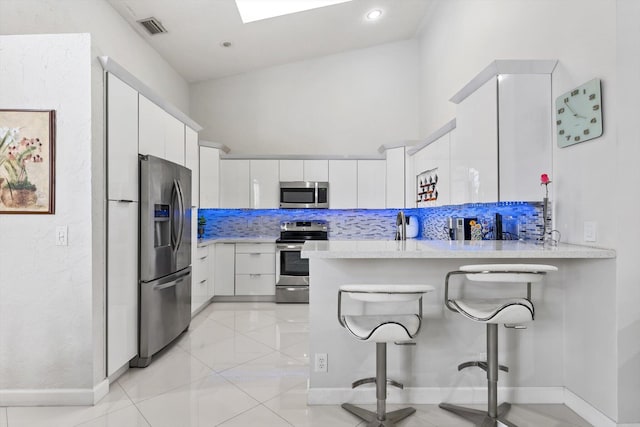 8237 Via Di Veneto, Boca Raton, FL 33496 - kitchen with stainless steel appliances, a peninsula, light countertops, white cabinetry, and a kitchen breakfast bar