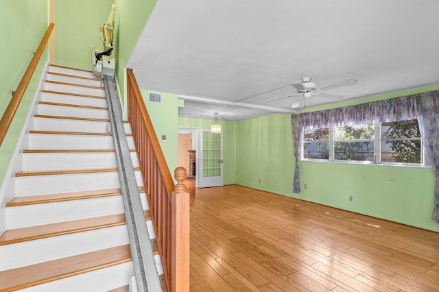 stairway with ceiling fan, wood-type flooring, and a chandelier