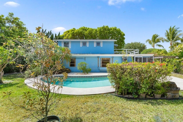 rear view of property with an outdoor pool and a lawn