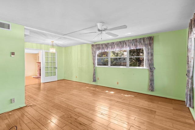 empty room with a ceiling fan, wood-type flooring, and a chandelier