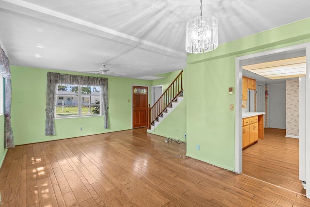 unfurnished living room with light wood-style floors, stairs, a chandelier, and a ceiling fan