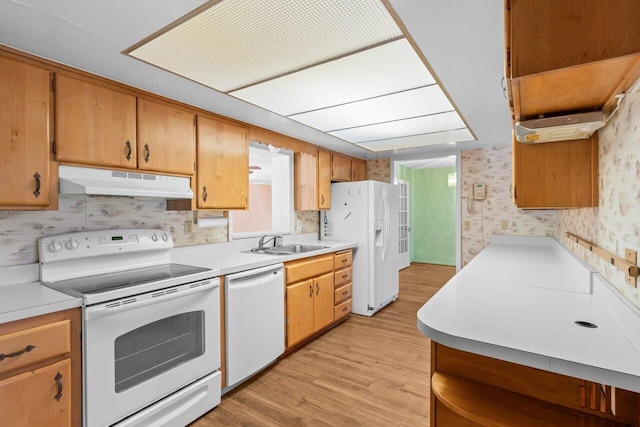 kitchen with white appliances, under cabinet range hood, wallpapered walls, a sink, and light wood-style flooring