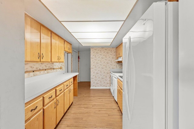 kitchen with freestanding refrigerator, wallpapered walls, light countertops, light wood-style floors, and under cabinet range hood
