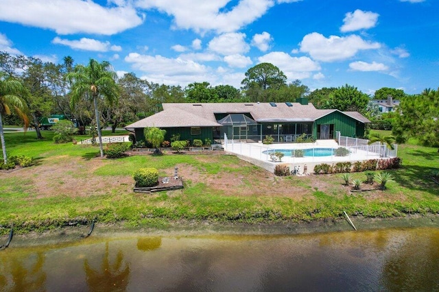 back of house with an outdoor pool, fence, a water view, and view of scattered trees