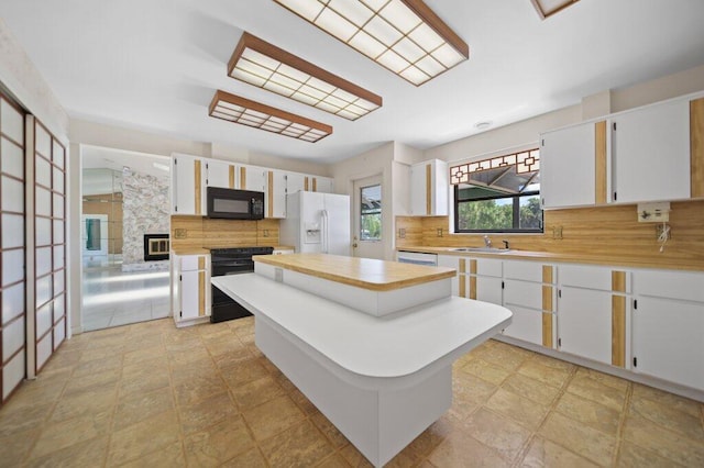 kitchen featuring white appliances, backsplash, light countertops, a center island, and a sink