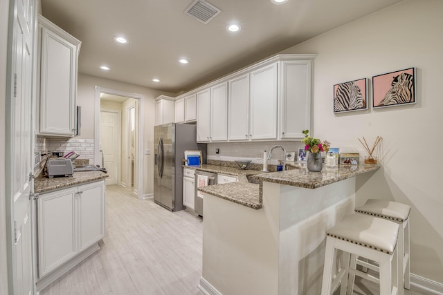 1330 S Jeaga Dr, Jupiter, FL 33458 - kitchen with a sink, appliances with stainless steel finishes, a peninsula, decorative backsplash, and white cabinetry