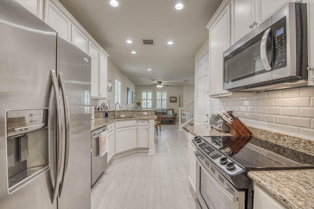1330 S Jeaga Dr, Jupiter, FL 33458 - kitchen with stainless steel appliances, a peninsula, white cabinetry, a sink, and recessed lighting
