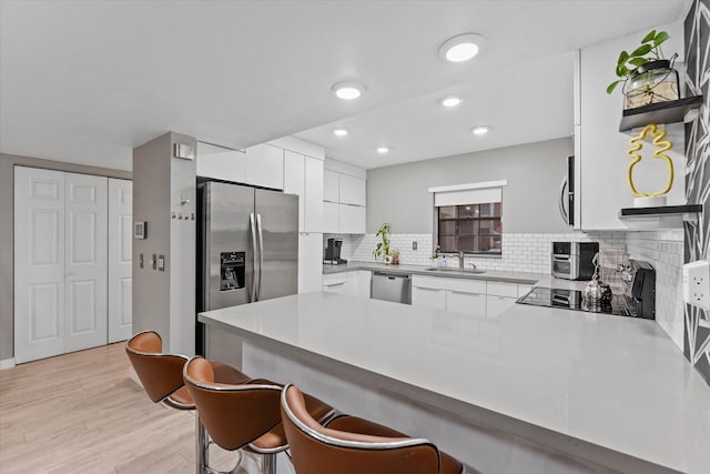 184 NW 115th Ter, Plantation, FL 33325 - kitchen with a peninsula, a sink, white cabinets, stainless steel appliances, and a breakfast bar