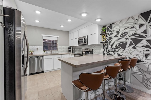 184 NW 115th Ter, Plantation, FL 33325 - kitchen featuring stainless steel appliances, a peninsula, a sink, white cabinets, and recessed lighting