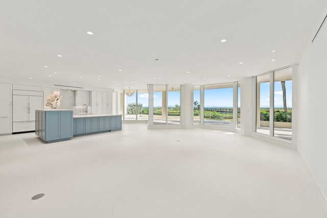 unfurnished living room with plenty of natural light, recessed lighting, floor to ceiling windows, and a sink