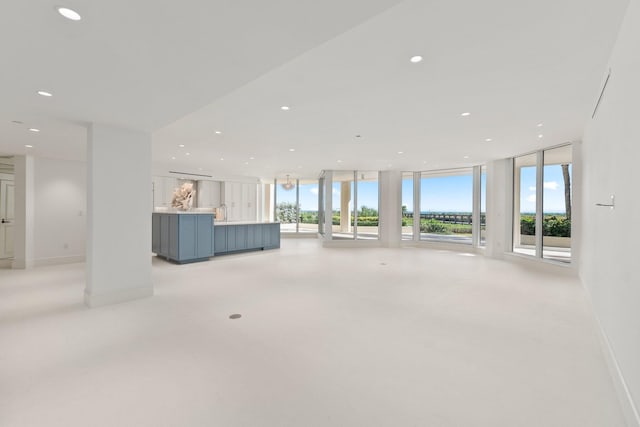 unfurnished living room with floor to ceiling windows, recessed lighting, and baseboards