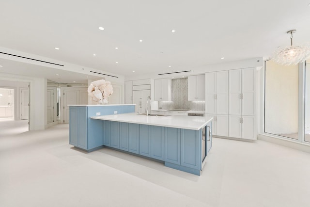 kitchen with a sink, white cabinetry, light countertops, a spacious island, and recessed lighting