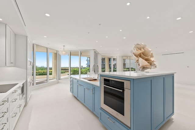 kitchen featuring a sink, oven, blue cabinetry, a spacious island, and light countertops