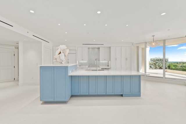 kitchen with light countertops, recessed lighting, a sink, decorative backsplash, and a spacious island