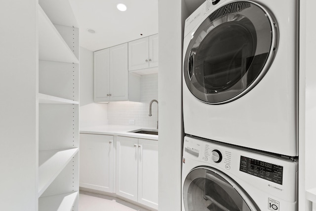 washroom with stacked washer and clothes dryer and cabinet space