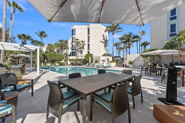 community pool with outdoor dining space, a patio area, and a pergola