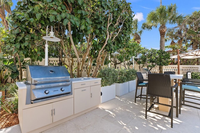 view of patio featuring area for grilling, fence, exterior kitchen, and outdoor dining area
