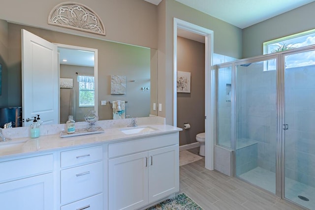 745 SE Bloomfield Rd, Port Saint Lucie, FL 34984 - bathroom with a stall shower, toilet, double vanity, and wood finish floors
