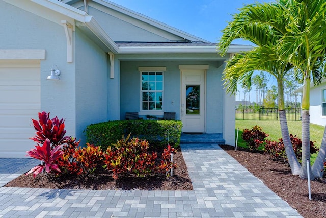 745 SE Bloomfield Rd, Port Saint Lucie, FL 34984 - doorway to property with fence, stucco siding, a garage, and covered porch