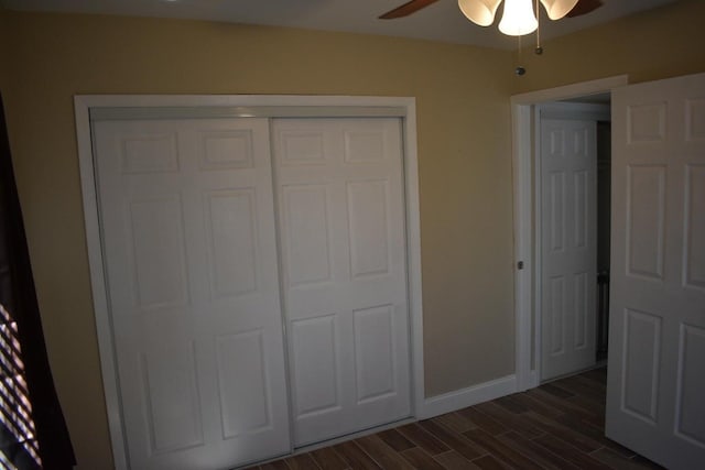unfurnished bedroom featuring baseboards, dark wood finished floors, a closet, and ceiling fan