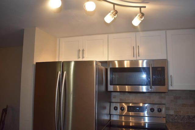 kitchen with appliances with stainless steel finishes, backsplash, and white cabinets